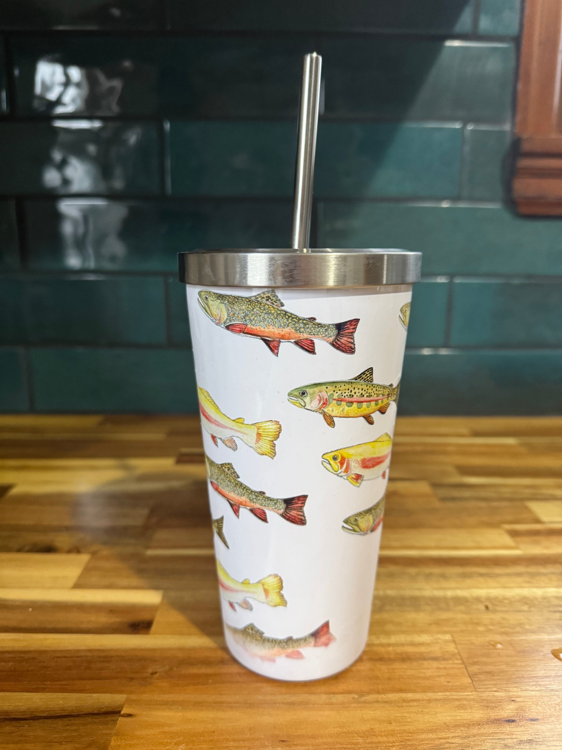 Tumbler with fish pattern on a wooden surface and green tiled wall background