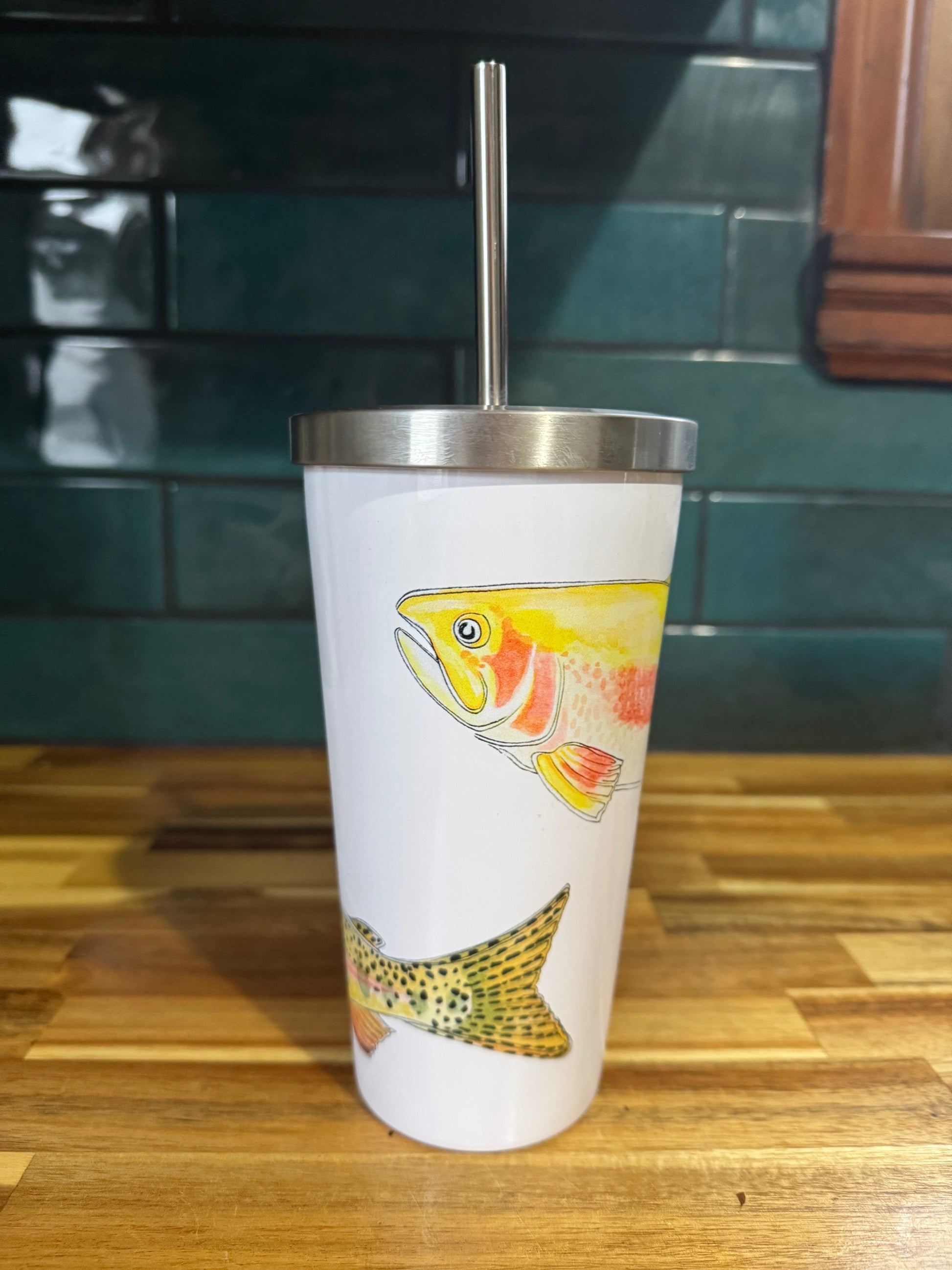 Tumbler with fish design on a wooden surface and green tiled wall background