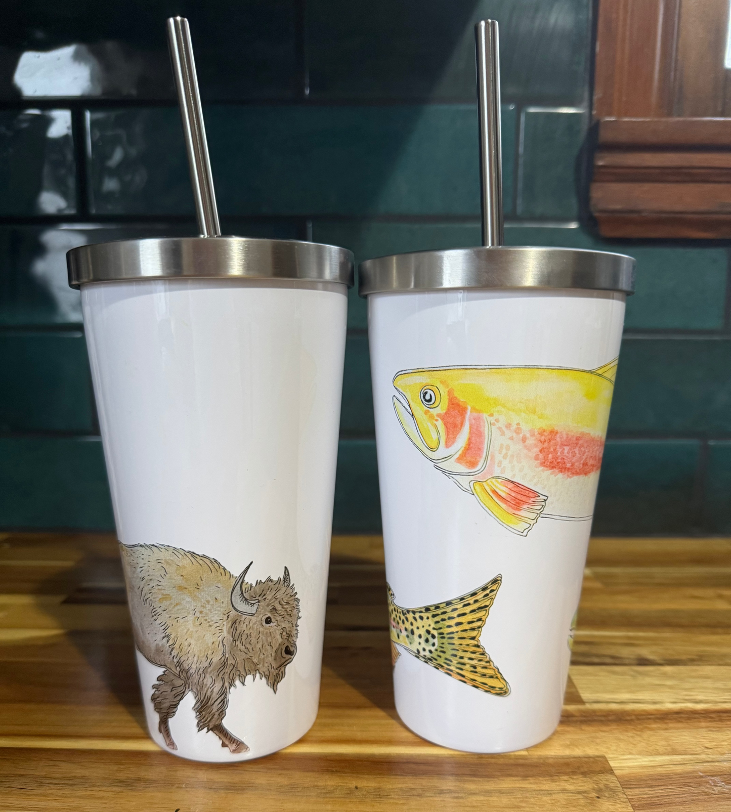 Two tumblers with animal illustrations on a wooden surface.