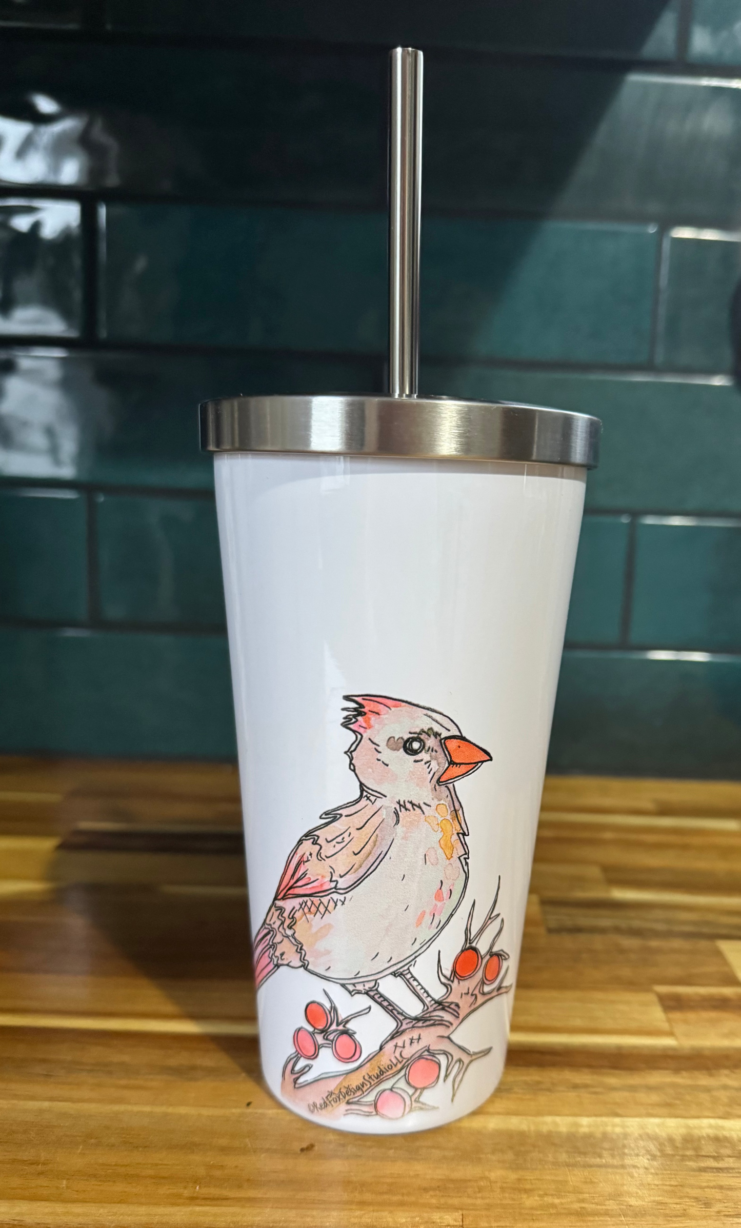Tumbler with a bird design on a wooden surface and tiled wall background